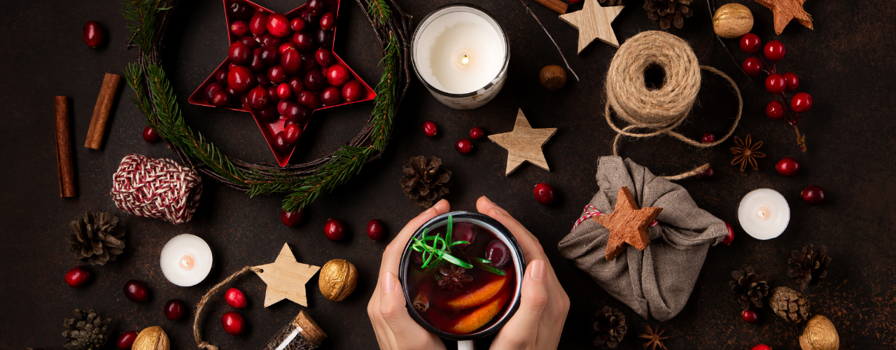 Mesa escura com elementos naturais de Yule — ramos de pinheiro, pinhas, bagas vermelhas, velas e canela