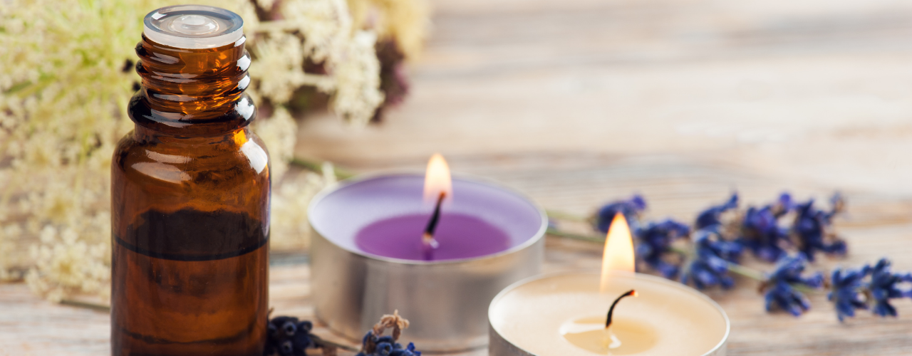 Frasco de óleo essencial, velas acesas e ramos de lavanda, ritual para preencher o espaço depois da limpeza energética