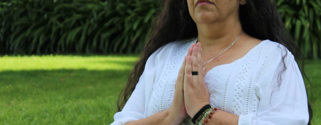Liliana Vieira com as mãos em prece, em momento de pausa e intenção interior — sobre chakras bloqueados e emoções acumuladas